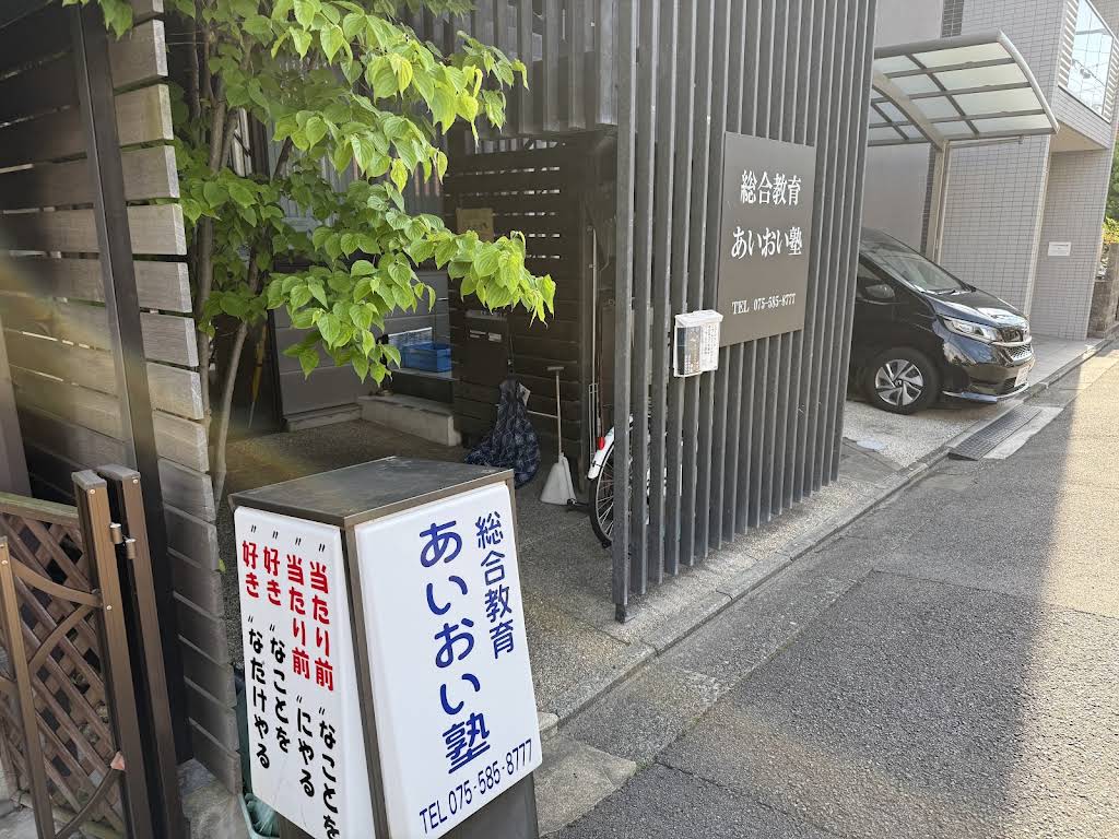 西院西今田町のあいおい塾入口。あいおい塾の看板と緑のある外観。